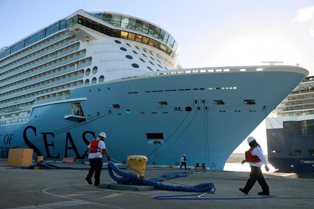 (FILES) In this file photo dock workers use ropes to tie the Royal Caribbean's Odyssey of The Seas to its berthing spot at Port Everglades on June 10, 2021 in Fort Lauderdale, Florida. – AFP