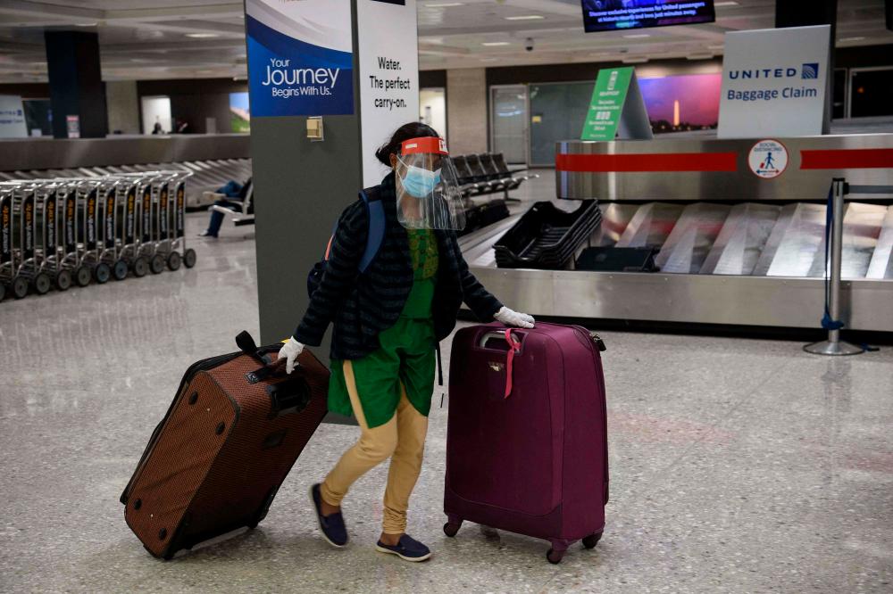 (FILES) In this file photo taken on November 24, 2020, a woman wheels her luggage at Washington’s Dulles International Airport in Dulles, Virginia. AFPpix