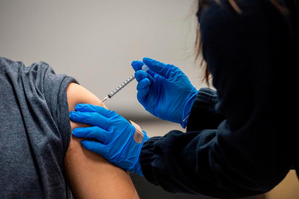 (FILES) In this file photo a man is inoculated with the Pfizer-BioNTech Covid-19 vaccine at La Colaborativa in Chelsea, Massachusetts. – AFP