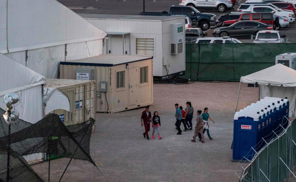 In this file photo taken on June 21, 2019 Immigrants are pictured behind the fences of a temporary facility set up to hold them at the El Paso Border Patrol Station. - AFP