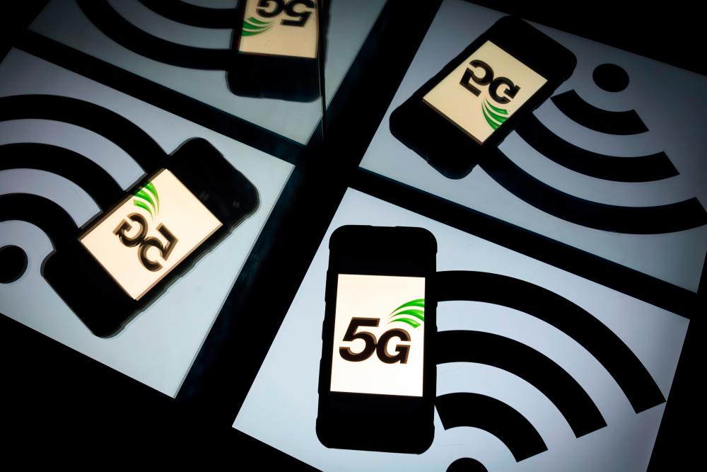 (FILES) In this file photo taken on February 16, 2019 this illustration picture shows the 5 G wireless technology logo displayed on a smartphone and a wireless signal sign displayed by a tablet in Paris. Apple is expected on October 13, 2020, to unveil a keenly anticipated iPhone 12 line-up starring models tuned to super-fast new 5G telecom networks in an update considered vital to the company’s fortunes. / AFP / Lionel BONAVENTURE