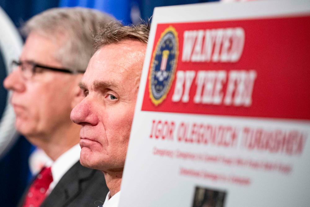 In this file photo taken on Dec 5, 2019, a law enforcement official listens as US and UK Law enforcement officials announce warrants for the arrests of Maksim Viktorovich Yakubets and Igor Olegovich Turashev, two Russian hackers associated with a group called Evil Corp., at the US Department of Justice in Washington, DC. — AFP