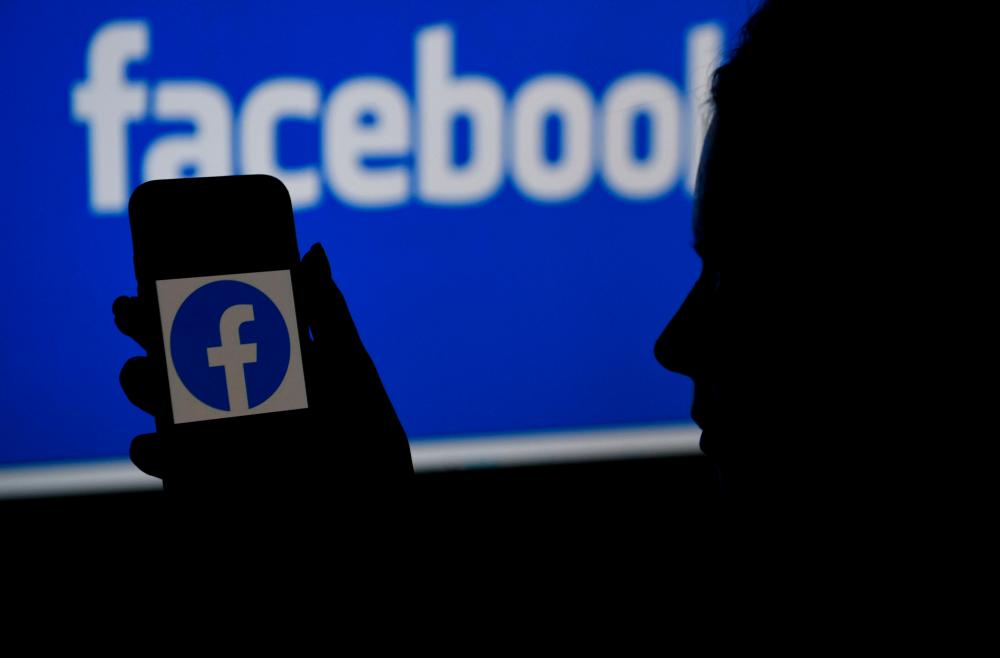 (FILES) In this file photo illustration, a smart phone screen displays the logo of Facebook on a Facebook website background. – AFP