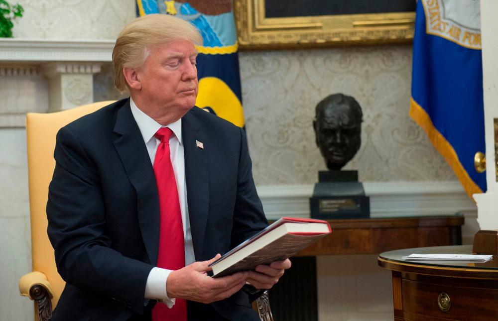 In this file photo taken on February 02, 2018 US President Donald Trump looks at a book given to him by a North Korean defector in the Oval Office at the White House in Washington, DC/AFPPix