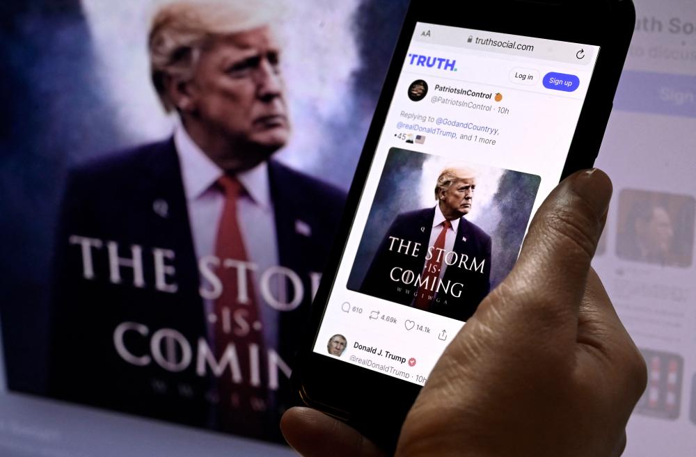 (FILES) In this file illustration photo taken on September 13, 2022 Donald Trump’s TRUTH Social account is seen on a mobile device with an image of former US president Donald Trump in the background in Washington, DC. AFPPIX