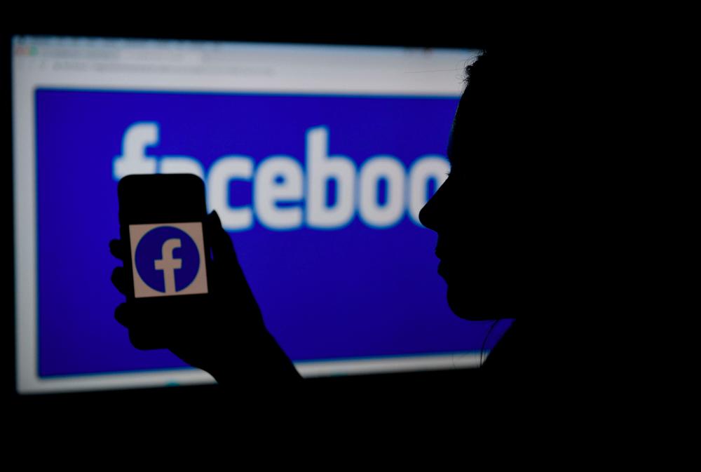 FILES) In this file photo illustration, a smart phone screen displays the logo of Facebook on a Facebook website background, on April 7, 2021. - AFP