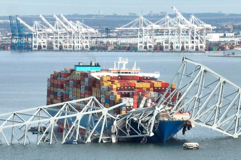 In this aerial image, the steel frame of the Francis Scott Key Bridge sits on top of a container ship after the bridge collapsed, Baltimore, Maryland, on March 26, 2024/AFPPix