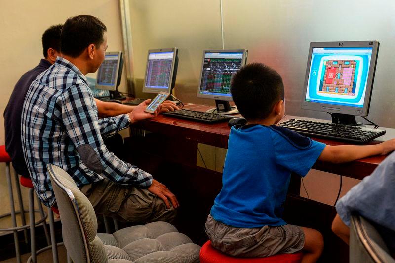 A child plays a game on a computer as investors look at share prices at a securities firm in Hanoi - AFPpix