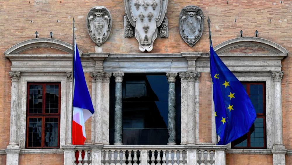 The French national flag and the EU flag (R) flutter outside the French Embassy at the Palazzo Farnese in Rome — AFP