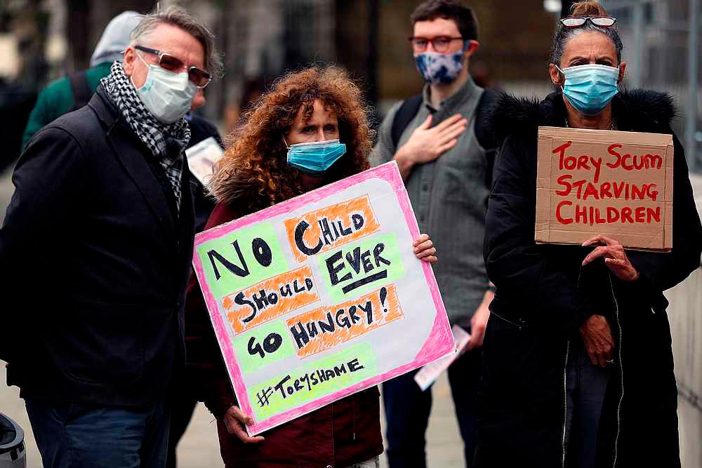 People hold banners during a protest demanding free school meals for children in England, in London, Britain October 24, 2020. — Reuters