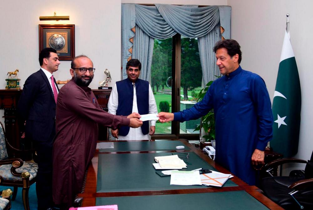 Pakistani Prime Minister Imran Khan receives a cheque from Head of the Edhi Foundation Faisal Edhi, for the Prime Minister's coronavirus disease (Covid-19) relief fund at the Prime Minister House in Islamabad, Pakistan April 15, 2020. - Reuters