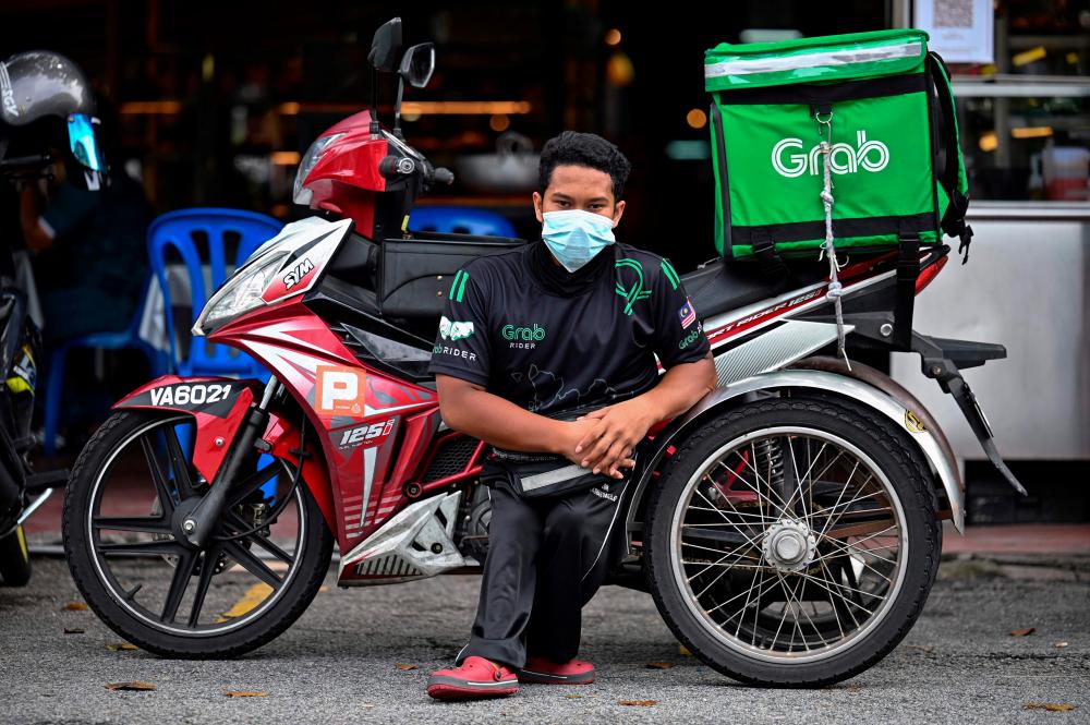 Muhammad Sidek Osman, a Grab food delivery man born disabled due to birth complications, posing with his modified motorbike in Gombak, Kuala Lumpur in this file picture. – AFP
