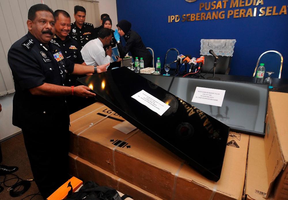 Penang police chief Datuk Seri A. Thaiveegan shows one of the LED TVs seized. — Bernama