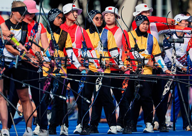 $!National archers Ariana Nur Dania Mohamad Zairi, Nurul Azreena Mohamad Fazil, and Syaqiera Mashayikh (from left, wearing yellow T-shirts) compete in the archery event at the Paris 2024 Olympic Games on the Esplanade des Invalides today. - BERNAMApix