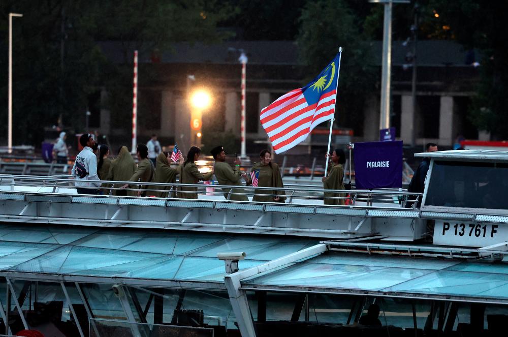 $!Malaysia’s Chef de Mission for the 2024 Paris Olympics, Datuk Hamidin Mohd Amin, along with Malaysia’s (Jalur Gemilang) flag-bearers, diving athlete Betrand Rhodic Lises and sailor Nur Shazrin Mohamad Latif, together with the national contingent’s athletes and officials, boarded a boat during the opening ceremony of the Paris 2024 Olympic Games on the Seine River today. - BERNAMApix