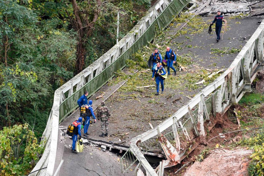 Rescuers walk on a suspension bridge which collapsed on Nov 18, in Mirepoix-sur-Tarn, near Toulouse, southwest France as they prepare to dive in the River Tarn. — AFP