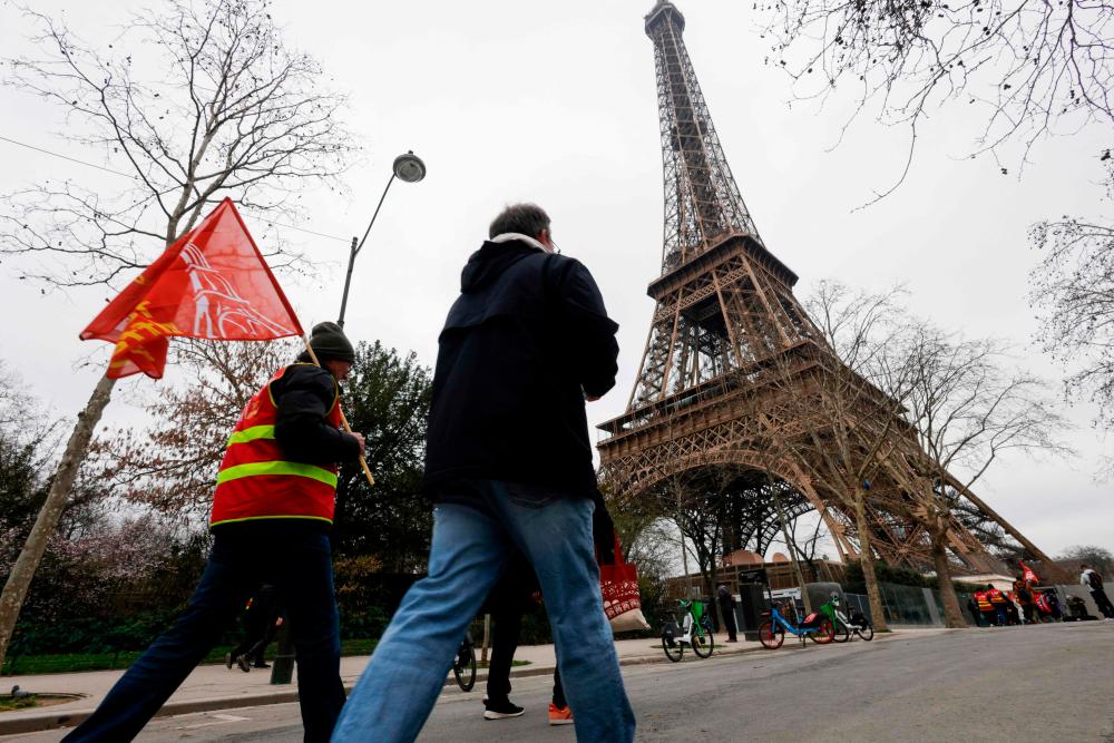 Protestors hold CGT unions flags with the Eiffel Tower in the background, during a strike of the Eiffel Tower’s staff, over the financial management of the monument by the city, closing the monument to the public during the second week of the French school holidays, in Paris on February 20, 2024/AFPPix