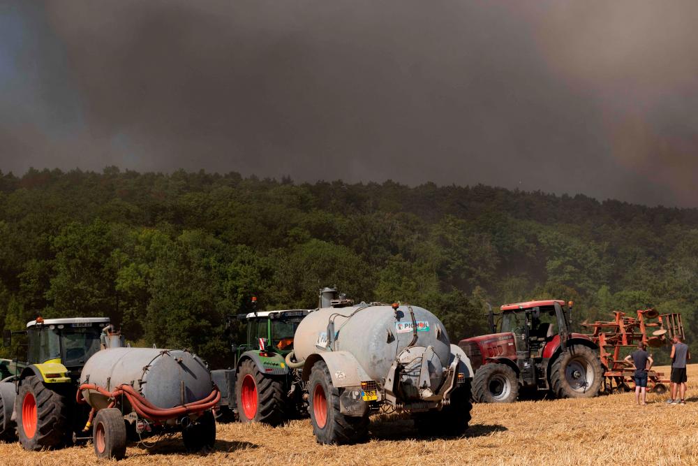 Farmers arrive with their water tank to prevent the spread of a forest fire and help firefighters in Thierville, in Normandy, northwestern France, on August 12, 2022. AFPPIX