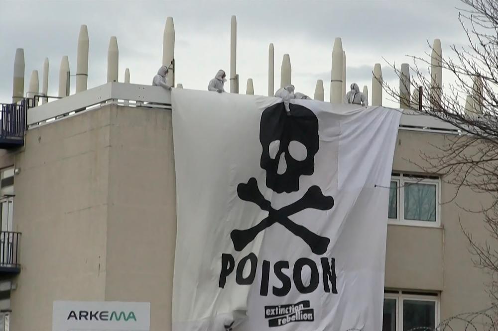 This image grab taken from AFPTV footage shows Extinction Rebellion and Youth for Climate activists deploying a giant banner depicting a skull and bones, bearing the message “Poison”, atop a structure inside the Arkema chemical plant after they entered the site to protest against pollution caused by polyfluoroalkyl substances (PFAS), in Pierre-Benite, south of Lyon, central-eastern France, on March 2, 2024/AFPPix