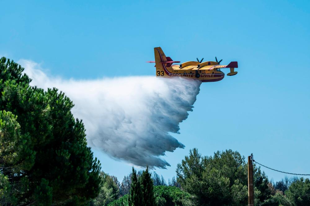 A picture taken on Aug 5, 2020, shows a Canadair bomber plane of the French Securite Civile droping water, a day after a wild fires broke out in La Couronne, near Marseille. — AFP