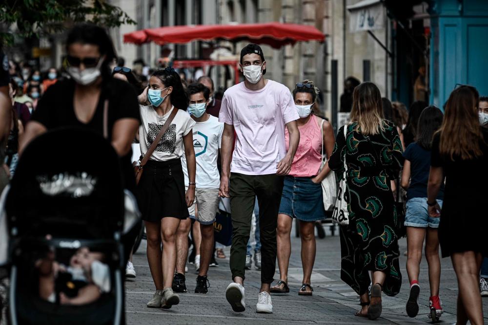 Pedestrians, some of them wearing protective face masks due to the Covid-19 coronavirus pandemic, walk in a street lined with shops in Bordeaux, southwestern France, on Sept 5, 2020. — AFP