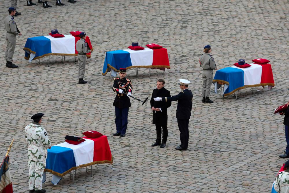 France's President Emmanuel Macron speaks in front of the coffin of the 13 French soldiers who died in a helicopter collision in Mali during the tribute ceremony at the Invalides monument in Paris on Dec 2, 2019. — AFP