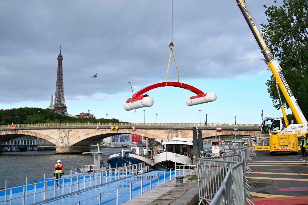 A worker dismantles a tempory venue to host a pre-Olympic swimming test competition on the river Seine after the event was cancelled due to pollution of the river in Paris on August 6, 2023. AFPPIX