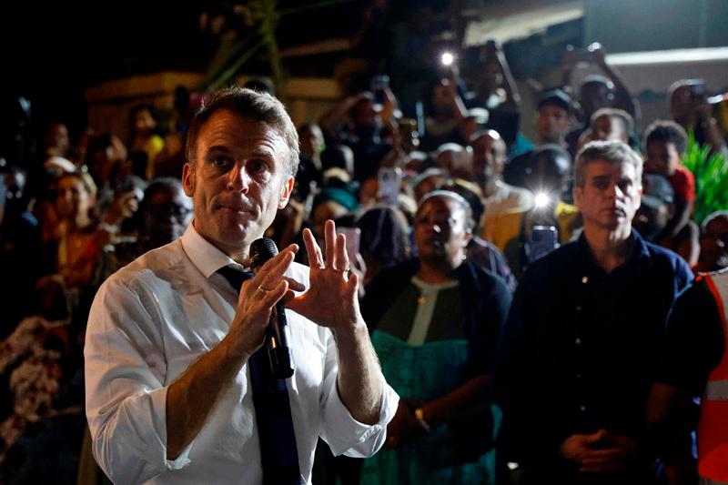 France's President Emmanuel Macron speaks to local residents during his visit in Pamandzi, on the French Indian Ocean territory of Mayotte on December 19, 2024. Distraught and angry inhabitants of Mayotte shouted out their despair to French President Emmanuel Macron during his visit on December 19, five days after the Indian Ocean archipelago was devastated by a cyclone, with lacking water and food, and fear of looting topping the grievances. - Ludovic MARIN / POOL / AFP