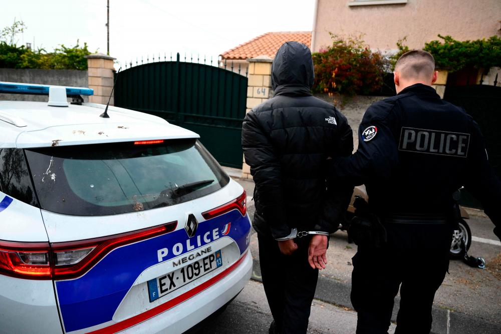 A young person is arrested for suspected drug trafficking by a policeman (R) from the unit “Brigade specialiste terrain” (BST 14) at the “Paternel” neighbourhood in the northern district of Marseille, southern France on March 31, 2023. AFPPIX
