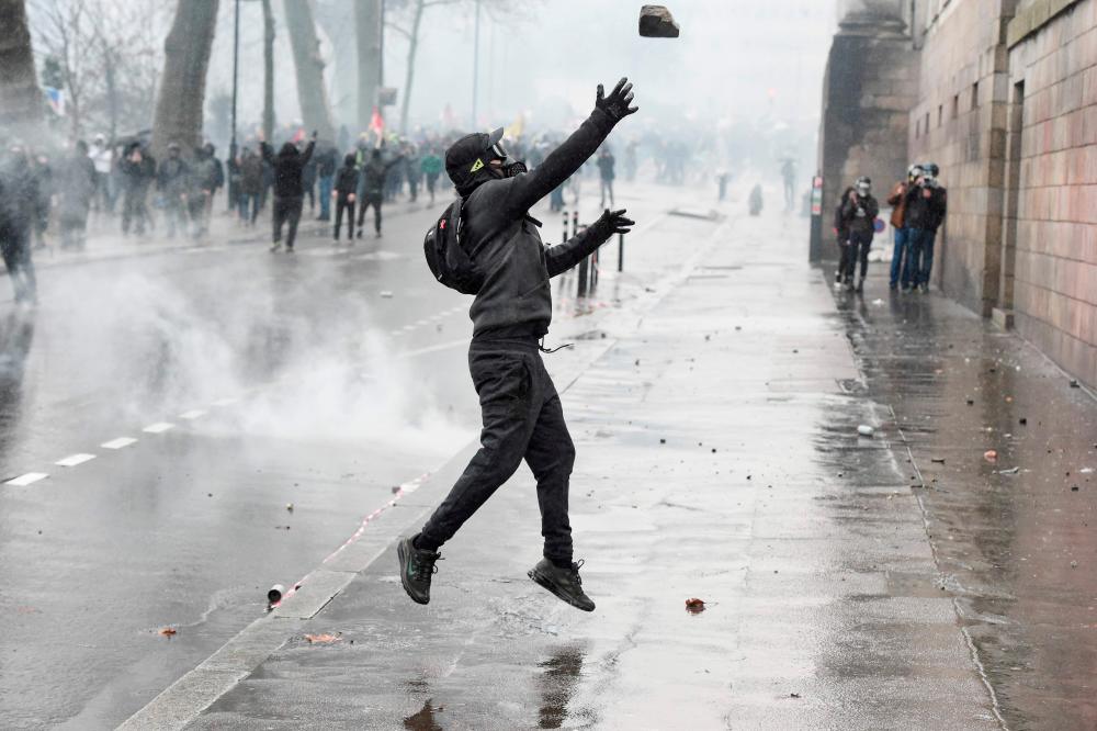 A protestor throws a rock towards French police during a demonstration on day 36 of a nationwide multi-sector strike over French government's plan to overhaul the country's retirement system in Nantes, western France on Jan 9. — AFP