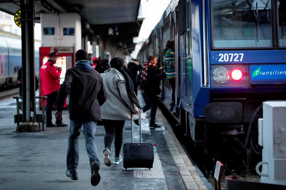 Passengers run on a platform to catch a train in the Gare de Lyon railway station in Paris on Dec 8, during a strike of state railway company SNCF employees over French government's plan to overhaul the country's retirement system, as part of a national general strike. — AFP
