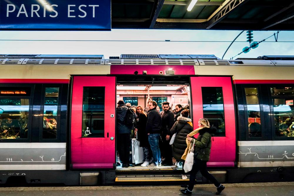 Commuters enter in a train at Gare de L'Est trains station in Paris, on Dec 13, 2019, during a strike of Paris' public transports operator RATP and of the French state railway company SNCF employees over French government's plan to overhaul the country's retirement system. — AFP