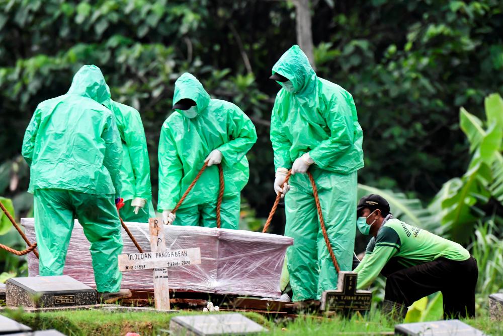 Workers prepare to bury the coffin of a coronavirus disease (Covid-19) victim at the Pondok Ranggon funeral area in Jakarta, Indonesia, March 30, 2020 in this photo taken by Antara Foto. - Reuters