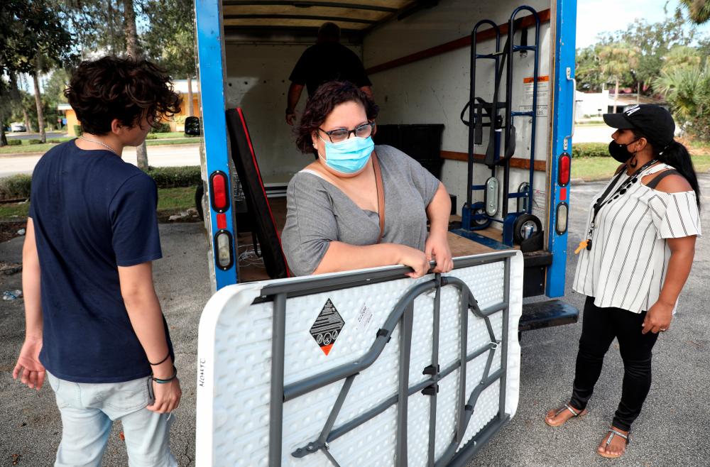 Lisandra Bonilla, who was furloughed from her job at an employment agency due to the coronavirus pandemic, helps set up the 'It Takes a Village' clothing and provisions outreach event in Kissimmee, Florida, on Oct 24. – REUTERSPIX