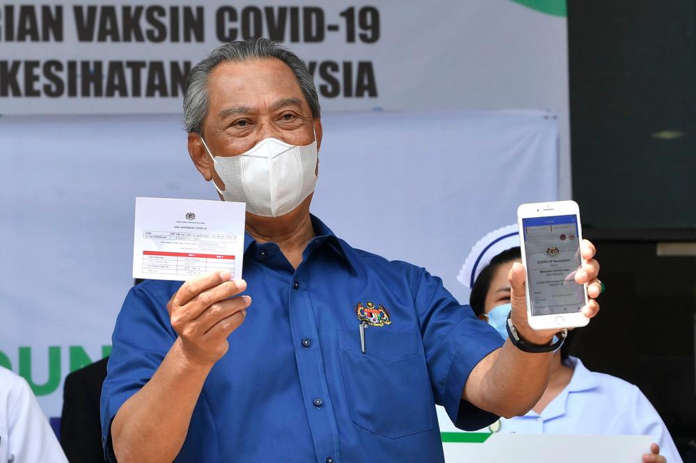 Prime Minister Tan Sri Muhyiddin Yassin showing the Vaccination Card and COVID-19 vaccination status displayed on MySejahtera application after receiving the Pfizer-BioNTech COVID-19 vaccine injection at the District Health Centre in Precinct 11 on Feb 24.- Bernama