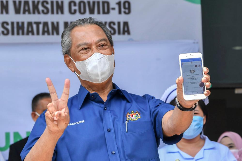 Prime Minister Tan Sri Muhyiddin Yassin looked cheerful while showing the COVID-19 vaccination status displayed on MySejahtera application after receiving the Pfizer-BioNTech COVID-19 vaccine injection at the District Health Centre in Precinct 11 on Feb 24 - Bernama.