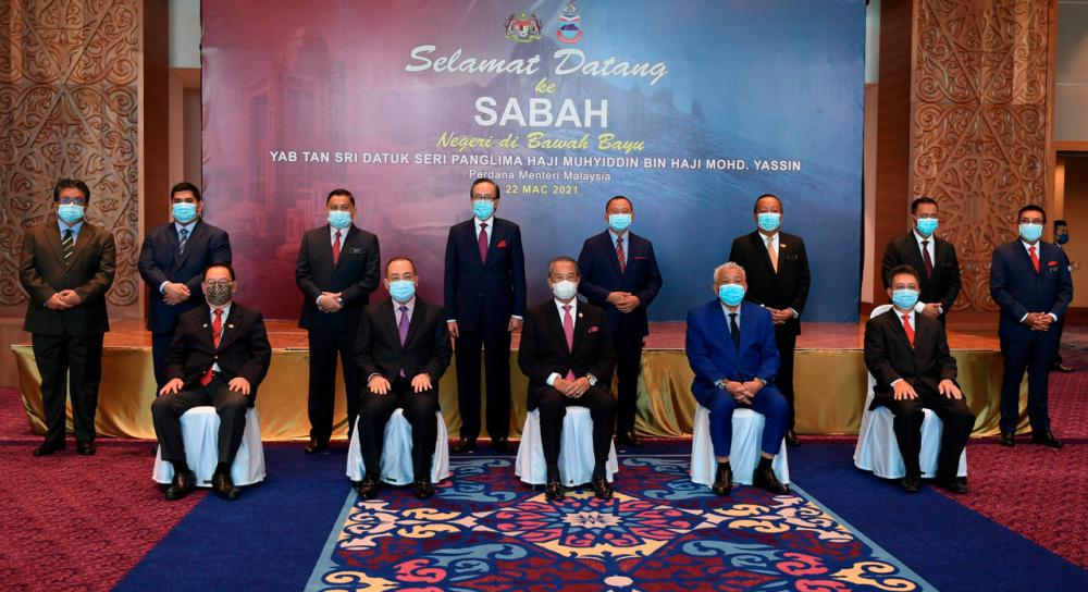 Prime Minister Tan Sri Muhyiddin Yassin (sitting middle) and Sabah Chief Minister Datuk Seri Hajiji Noor (sitting left) taking a photo with the Sabah state cabinet before attending the state development briefing at Chief Minister Office, Sabah State Administrative Centre on March 22. - Bernama