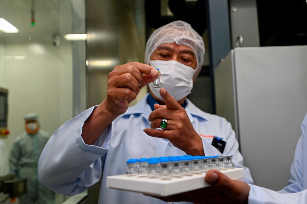 Prime Minister Tan Sri Muhyiddin Yassin inspecting the vial of the Covid-19 Sinovac vaccine bottled by Pharmaniaga LifeScience Sdn Bhd during his visit to the pharmaceutical company at Taman Perindustrian Puchong Utama on July 17.- Bernama