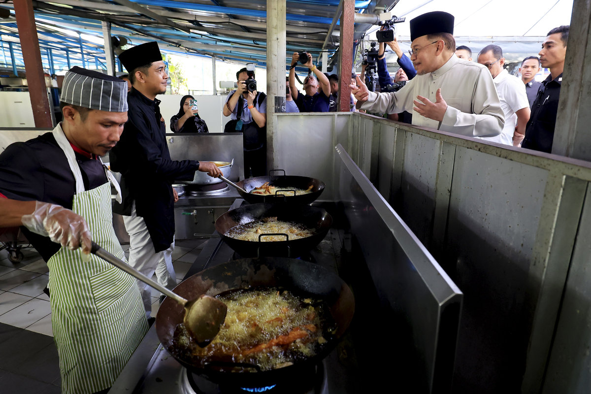 Perdana Menteri Datuk Seri Anwar Ibrahim beramah mesra bersama tukang masak di Restoran Pak Zain Patin di Jalan Kampung Orang Asli Bukit Dugang untuk menikmati makan tengah hari, hari ini. - BERNAMApix