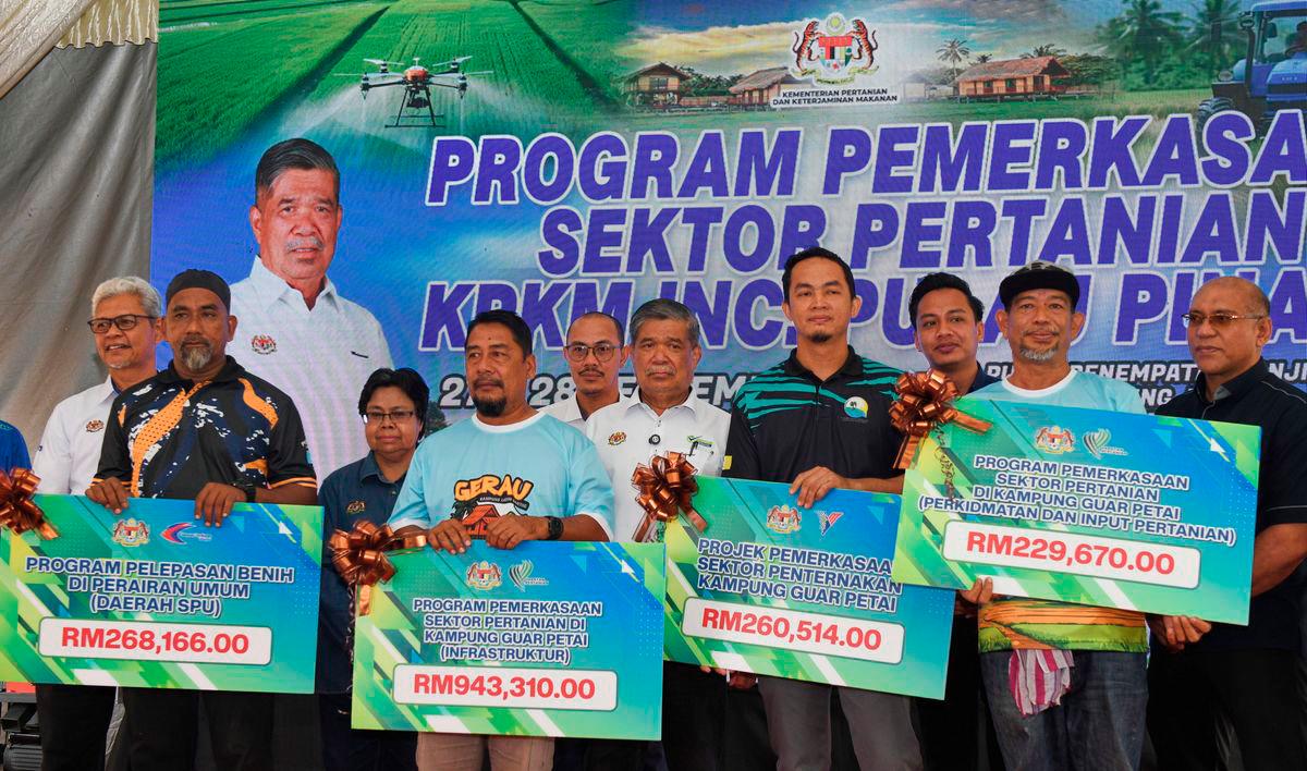 Minister of Agriculture and Food Security, Datuk Seri Mohamad Sabu (centre), with recipients of assistance under the Agricultural Sector Empowerment Programme by the Ministry of Agriculture and Food Security at the Kampung Labuh Banting Flood Resettlement Centre today. – BERNAMA