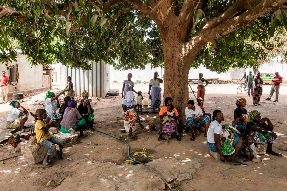Internally displaced Gambians sit under a tree after arriving in the village of Bujinha on March 15, 2022. AFPPIX