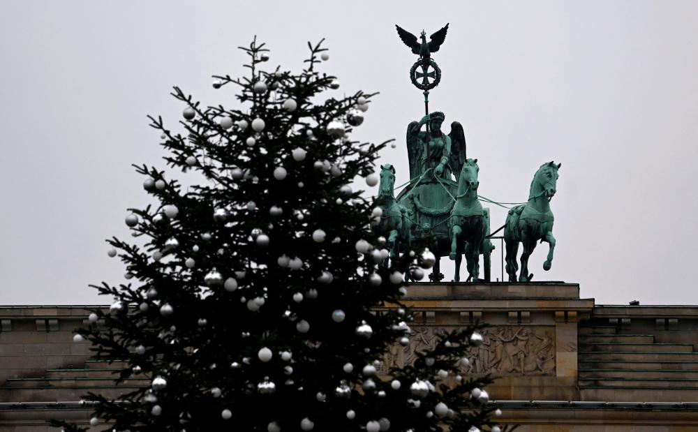 A Christmas tree with its top chopped off is seen in front of Berlin’s landmark the Brandenburg Gate on December 21, 2022/AFPPix