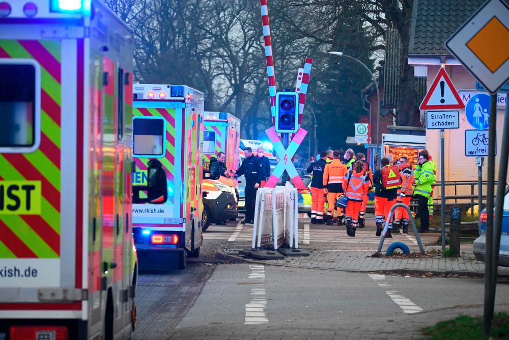 Rescue teams, ambulances and police stand at a railway crossing at the station of Brokstedt, northern Germany, on January 23, 2023, after a man stabbed people on a regional train between the cities of Hamburg and Kiel, killing two people and wounding several otrhers. AFPPIX