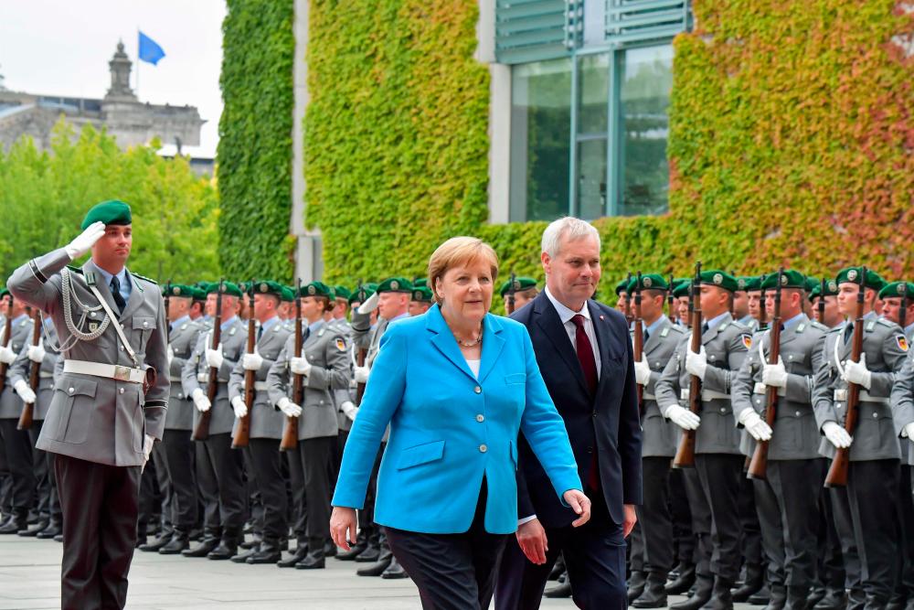 German Chancellor Angela Merkel and Finland's Prime Minister Antti Rinne review an honour guard during a welcoming ceremony with military honours at the Chancellery in Berlin on July 10, 2019. — AFP