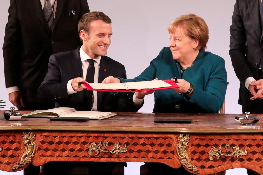 French President Emmanuel Macron and German Chancellor Angela Merkel exchange the French-German friendship treaty during the signing ceremony, on Jan 22, 2019 in the town hall of Aachen, western Germany. — AFP
