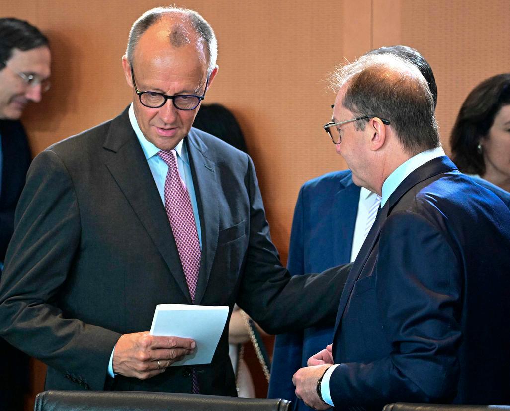 German Chancellor Friedrich Merz (L) talks with German Interior Minister Alexander Dobrindt before attending the weekly meeting of the German cabinet at the Chancellery in Berlin on July 2, 2025. (Photo by Tobias SCHWARZ / AFP)