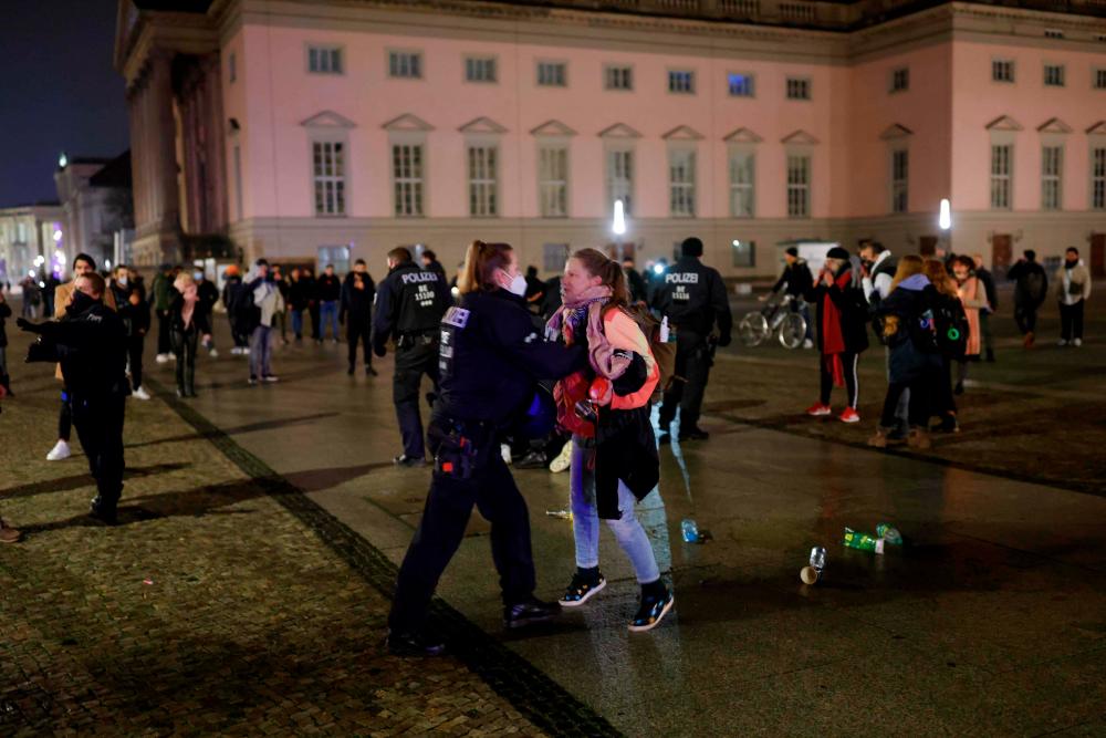 $!A woman (R) has an altercation with a policewoman at Bebelplatz square, after police tried to disperse a crowd of revellers at the Unter den Linden boulevard, following New Year celebrations at the Brandenburg Gate in Berlin, on early January 1, 2021. / AFP / Odd ANDERSEN