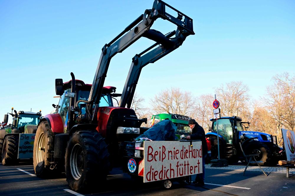 A placard reading ‘Don’t bite the hand that feeds you’ is attached on a tractor parked at the “Strasse des 17 Juni” boulevard, towards the Brandenburg Gate in Berlin, on January 8, 2023, during a protest against the federal government’s austerity plans/AFPpix