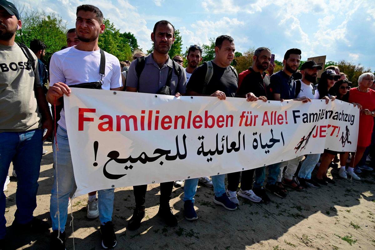 Demonstrators hold a banner reading in German and in Arabic Familz life for all! Family reunification now! as they protest in front of the Reichstag building that houses the Bundestag (lower house of parliament) against the German government's migration policy, on June 26, 2025 in Berlin. - AFPPIX