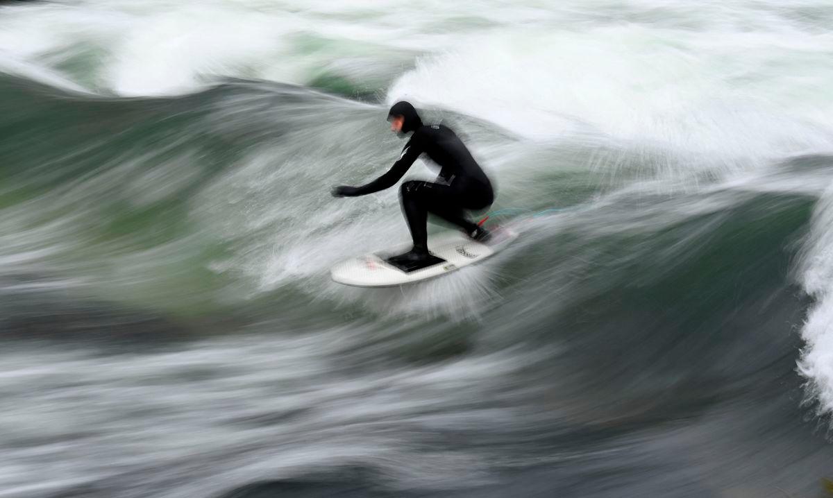 (FILES) Picture taken with long time exposure shows a surfer riding on an artificial wave in the canal of the Eisbach river at the English Garden park in Munich, southern Germany, during winter weather with temperatures by minus two degrees on January 16, 2021 - Photo by Christof STACHE / AFP